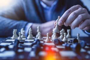 partial view of person moving chess piece on chess board